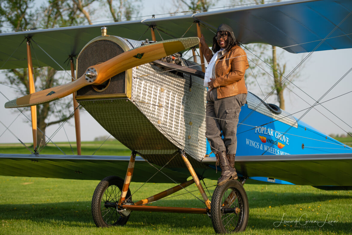 Gigi Coleman, great niece of pioneering 1920s stunt pilot Bessie Coleman, stands on a biplane emulating an iconic photograph of her great aunt.